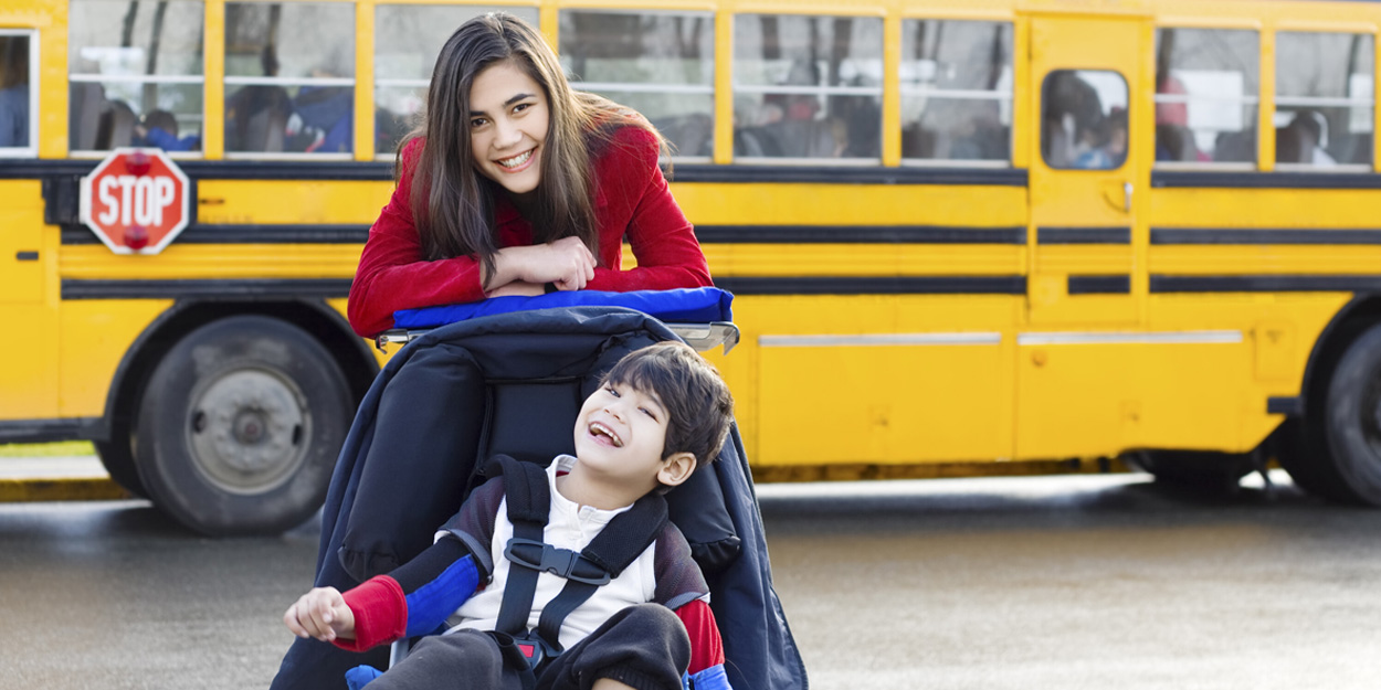 Student and teacher by a school bus